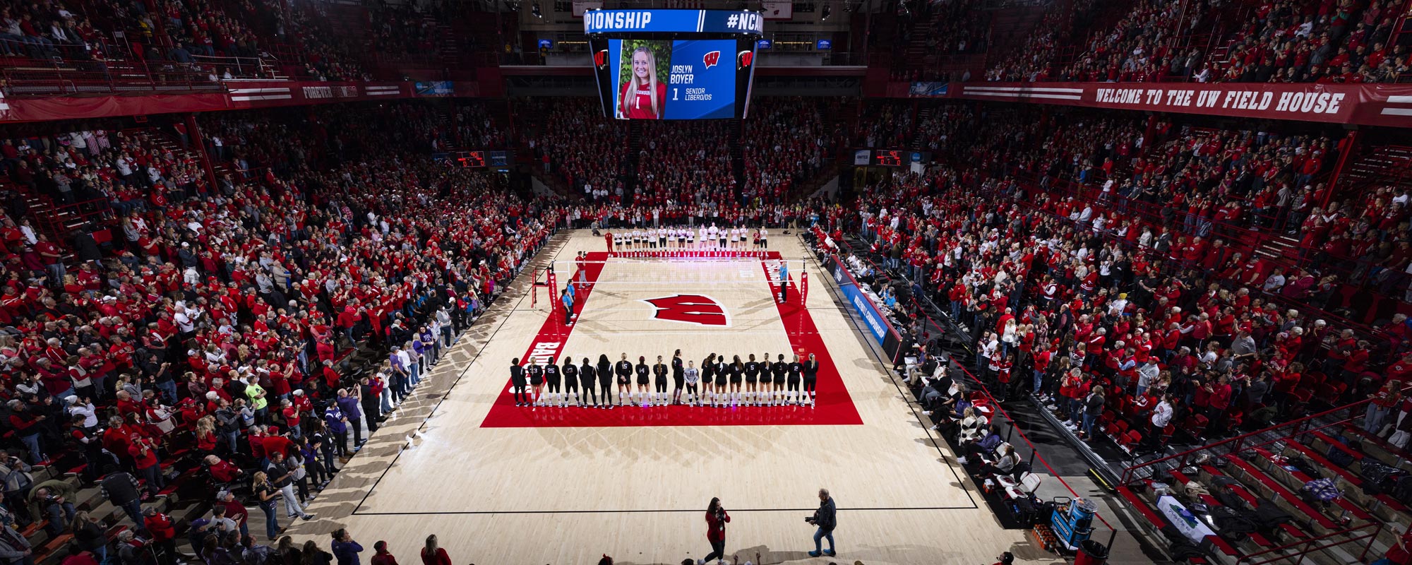 A photo of a Women's Volleyball Game At the Field House from high up in the stands looking down at the court.